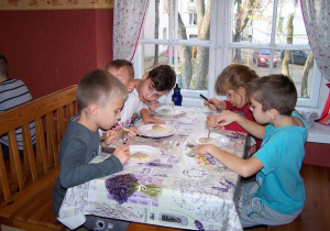 Pięcioro uczniów siedzi przy stole, z apetytem degustują własnoręcznie ulepione pierogi.