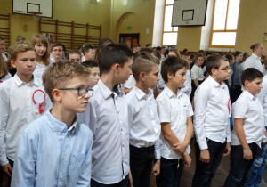 Uczniowie szkoły oglądający apel, przygotowujący się do odśpiewania Hymnu Polski.