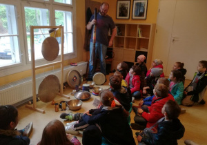 Sala muzyczna, uczniowie z zaciekawieniem słuchają opowieści artysty o niezwykłych instrumentach egzotycznych.