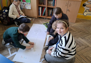 Sala lekcyjna, uczniowie podczas pracy w grupach składają schemat budowy człowieka.
