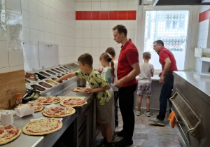 Kuchnia, uczniowie wyrabiają i przygotowują swoją pizzę.
