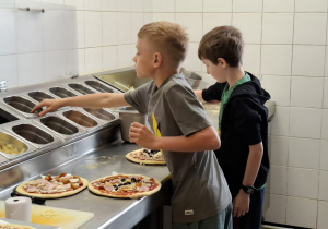 Kuchnia, uczniowie wyrabiają i przygotowują swoją pizzę.