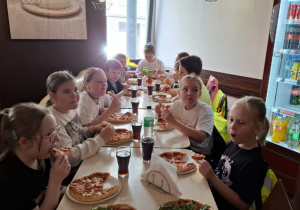 Pizzeria, uczniowie wspólnie degustują samodzielnie przygotowane przez siebie pizzę.